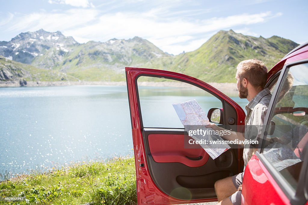 Junger Mann mit Bart auf road trip consulting Karte für die Anfahrt