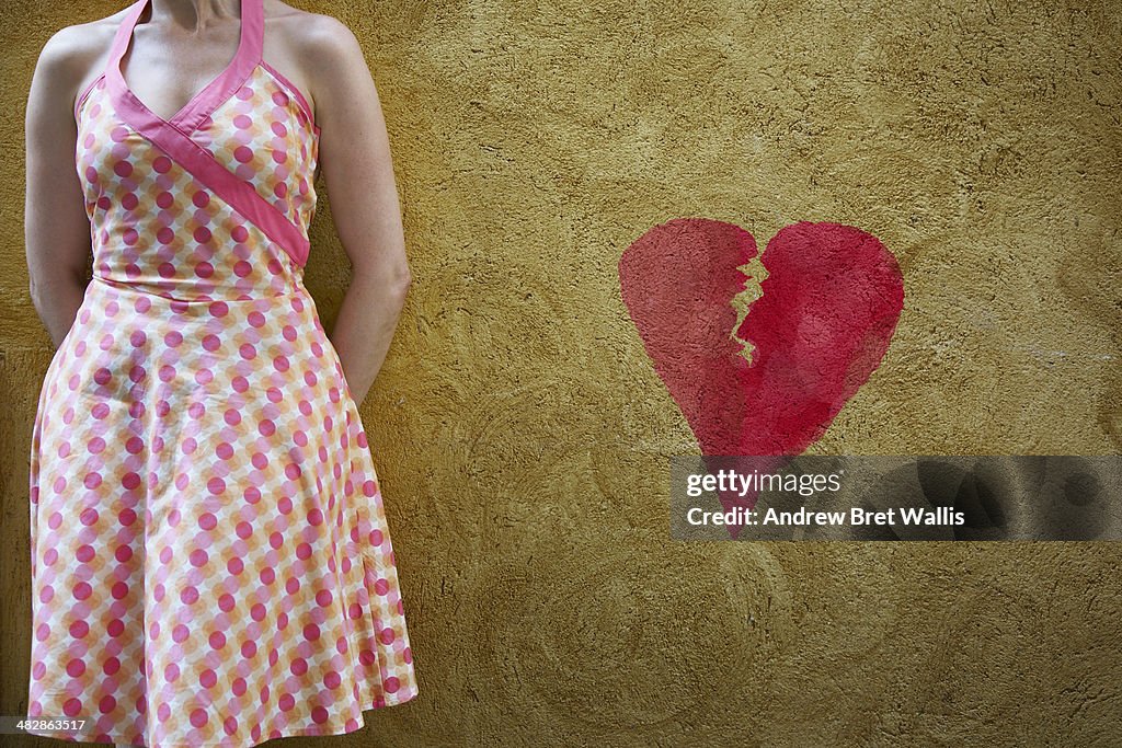 Woman and graffiti heart against a plaster wall