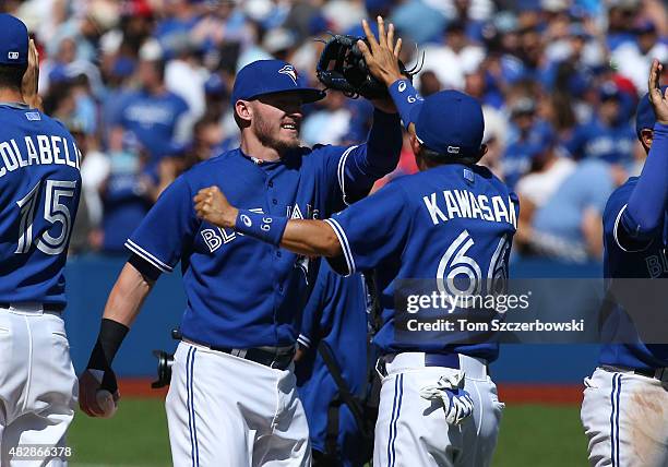 Josh Donaldson of the Toronto Blue Jays celebrates their victory with Munenori Kawasaki during MLB game action against the Minnesota Twins on August...