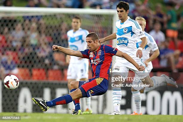 Josh Mitchell of the Jets kicks the ball ahead of Guilherme Finkler of the Victory during the round 26 A-League match between the Newcastle Jets and...