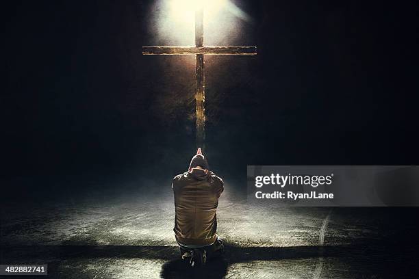 homem ajoelhar antes de cruz - louvar religião imagens e fotografias de stock