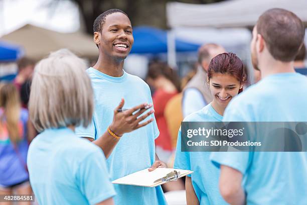 volunteer leader giving instructions at outdoor festival or market - 傳統節日 個照片及圖片檔
