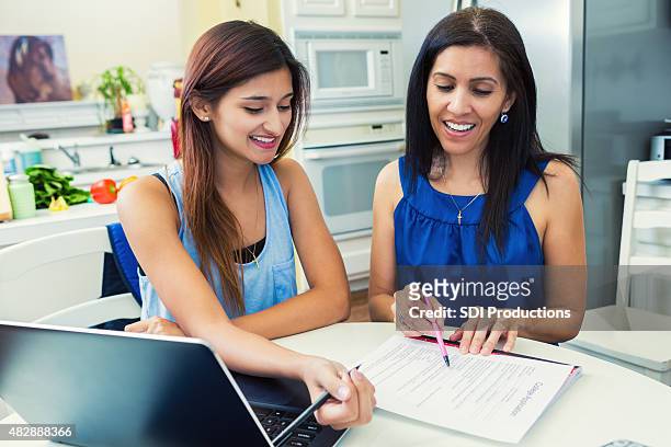 madre ayudando a su hija complete college aplicaciones en la cocina - form filling fotografías e imágenes de stock