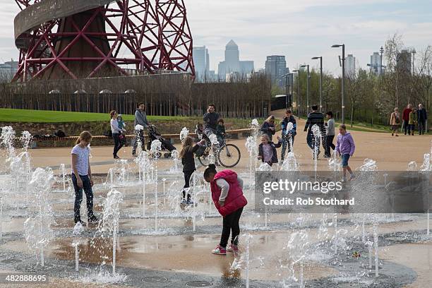 Children play in fountains in front of the 114.5 metre high ArcelorMittal Orbit tower at the Olympic Park on April 5, 2014 in London, England. The...