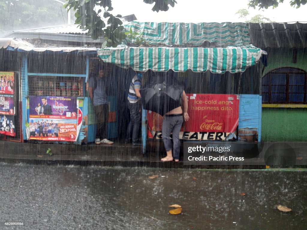 A Filipino holding a black umbrella walks along a narrow...