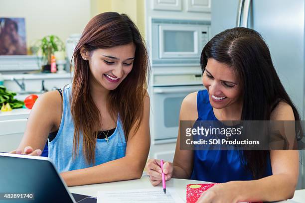 mature mother helping daughter fill out college application - college application stockfoto's en -beelden