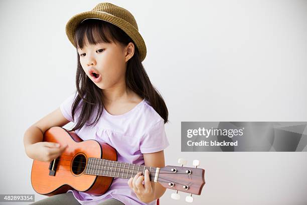 little chinese girl singing and playing ukulele - girl singing stock pictures, royalty-free photos & images