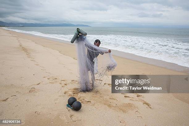 Burmese fisherman collects his nets after fishing on the beach where the Dawei deep sea port is planned to be built on August 3, 2015 in Nabule,...