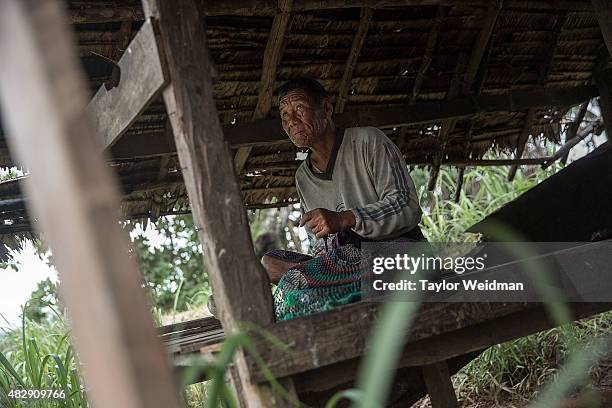 Burmese man relaxes in a small hut while waiting on the water buffalo he is tending inside the planned Dawei SEZ on August 2, 2015 in Nabule,...