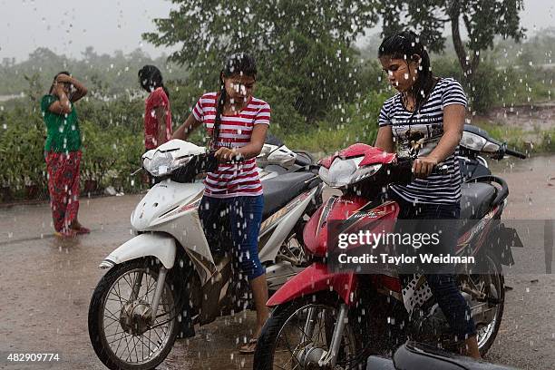 Burmese women start their bikes during a heavy rainstorm outside a market in the planned Dawei SEZ on August 2, 2015 in Nabule, Myanmar. The...