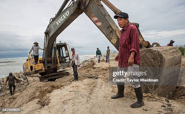 Construction workers try to fix a broken piece of equipment while working on the construction of a small, interim port inside the planned Dawei SEZ...