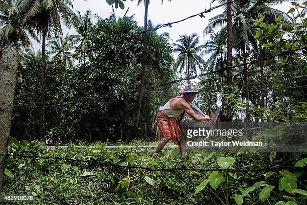 An employee of a coconut farm clears roadside brush in his village near the planned Dawei SEZ on August 4, 2015 in Pantininn, Myanmar. The...