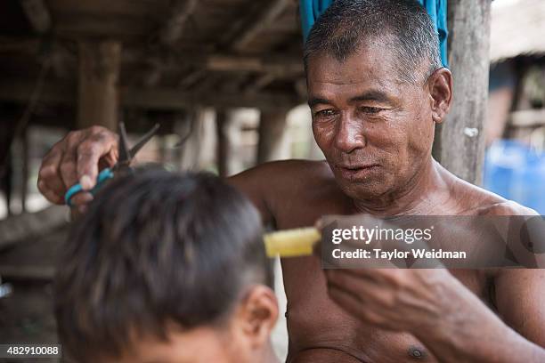 Burmese man cuts a boy's hair in a fishing village near the planned Dawei SEZ on August 3, 2015 in Pantininn, Myanmar. The controversial,...