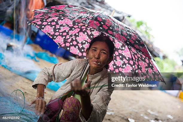 Burmese woman looks at the camera as she removes fish from netting near the planned Dawei SEZ on August 4, 2015 in Maungmagan, Myanmar.The...