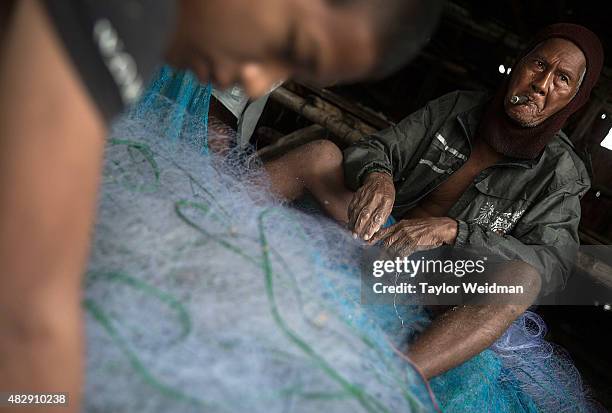 Burmese men and women remove fish from netting near the planned Dawei SEZ on August 4, 2015 in Maungmagan, Myanmar.The controversial, multi-billion...