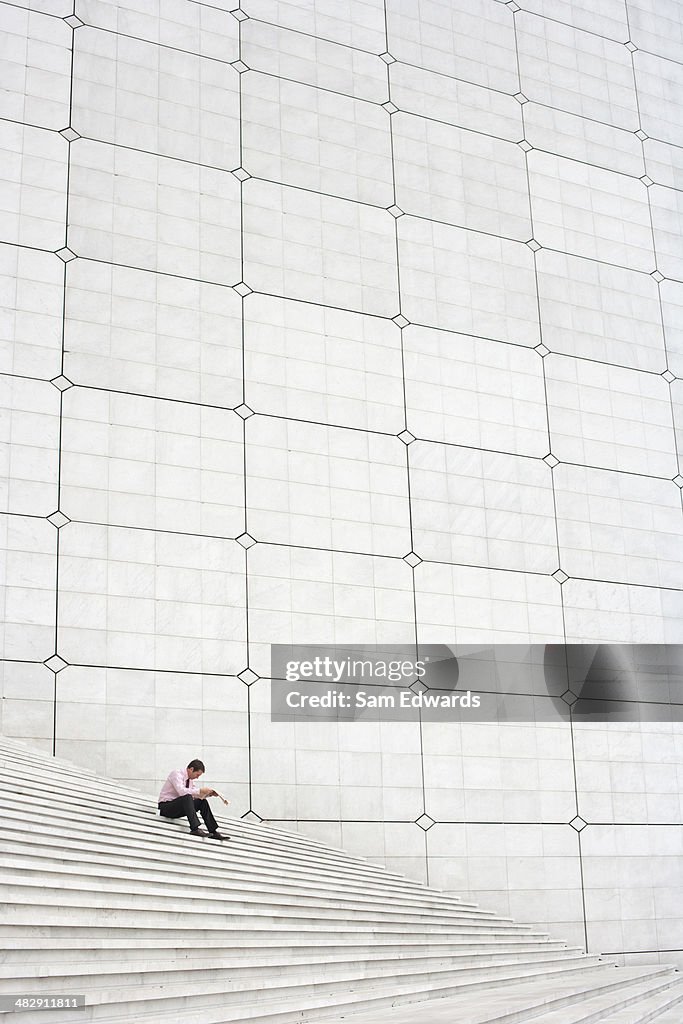 Businessman outdoors on staircase reading newspaper