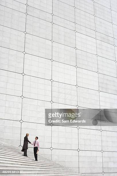 two businesspeople outdoors on staircase shaking hands - the paris agreement stock pictures, royalty-free photos & images