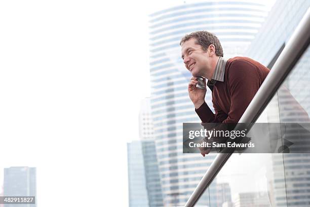 uomo d'affari sul balcone con il suo telefono cellulare - high key foto e immagini stock