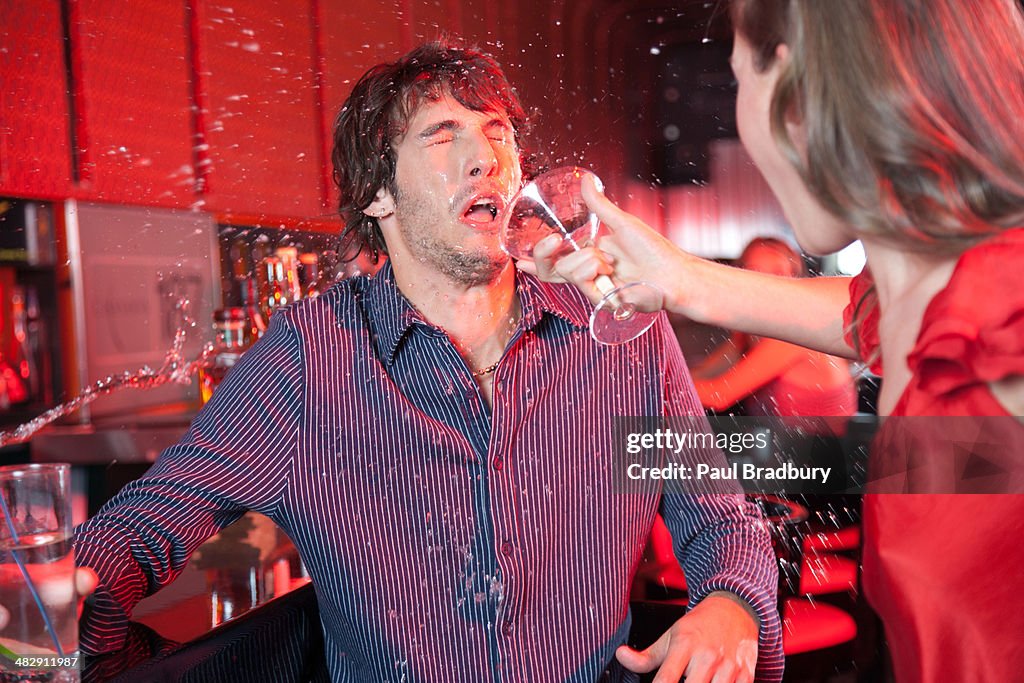 Mujer en un club nocturno tirando bebida en man's face