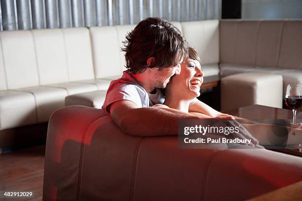 couple relaxing on living room sofa with red wine on table - young couple date night wine stock pictures, royalty-free photos & images