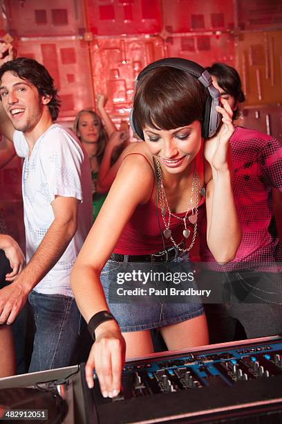 disc jockey in nightclub with people dancing around her smiling - dj booth stockfoto's en -beelden