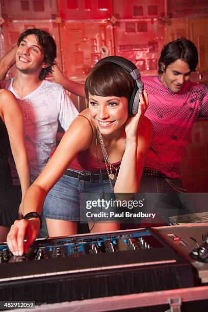 disc jockey in nightclub with people dancing around her smiling - dj booth stockfoto's en -beelden