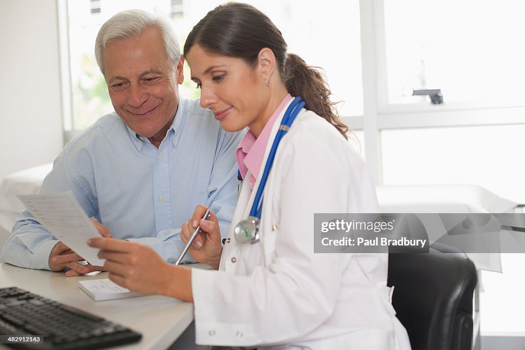 Arzt Sitzen im Büro mit Patienten reden und hält Papier