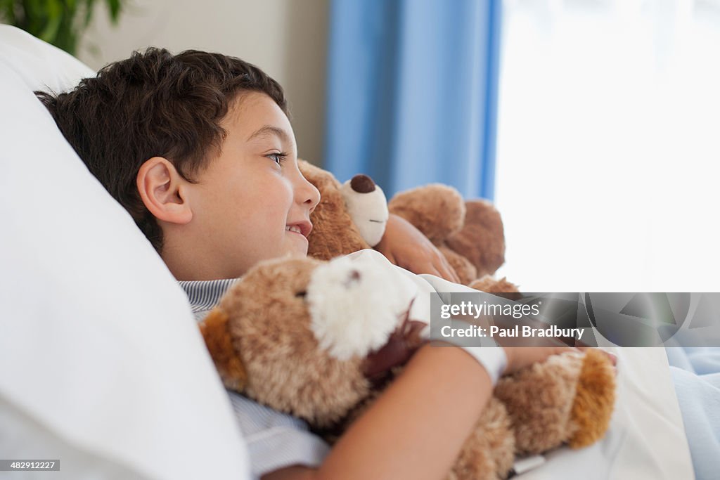 Young boy in hospital bed with teddy bears