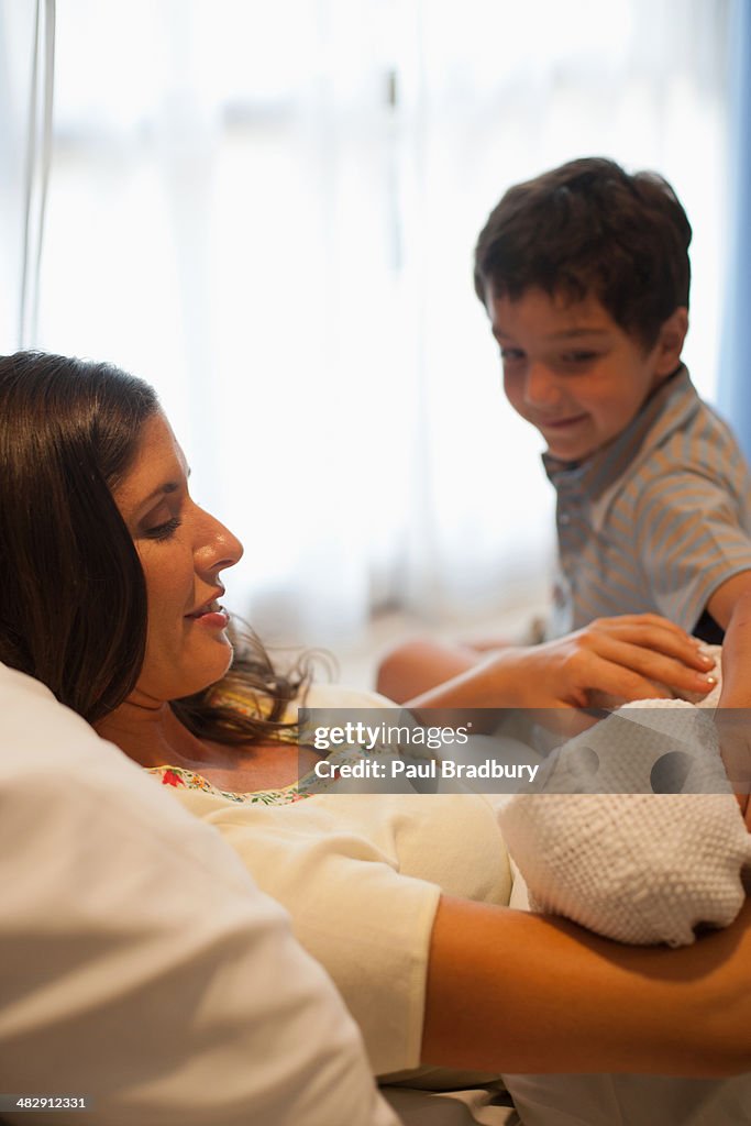 Frau holding Neugeborenes baby im Krankenhaus Bett lächelnd