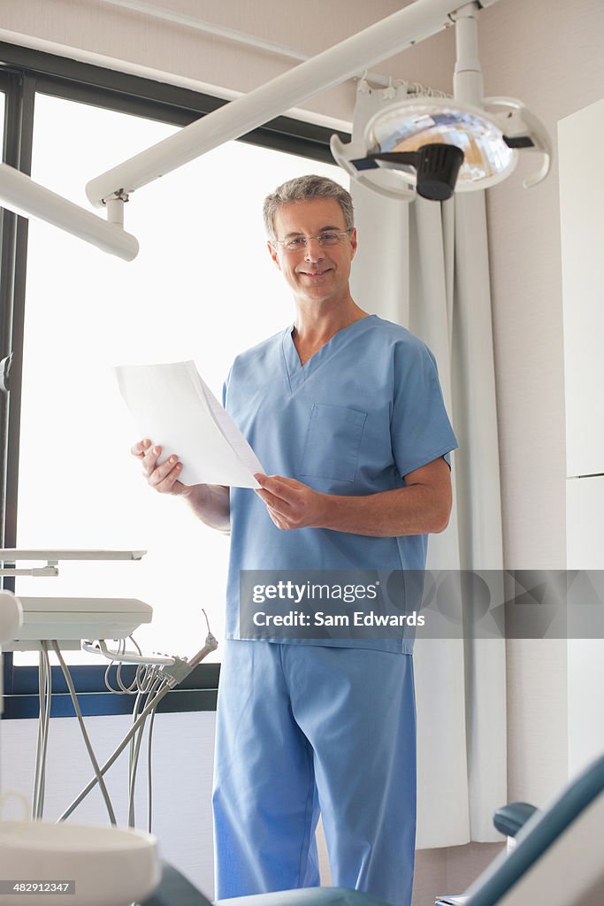 Dentist standing in examination room looking at charts