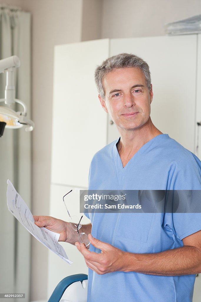 Dentista na sala de exame pé olhando para gráficos