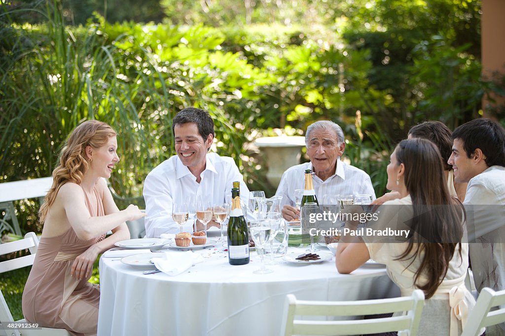 Grupo de pessoas sentado ao ar livre à Mesa a falar e sorrir