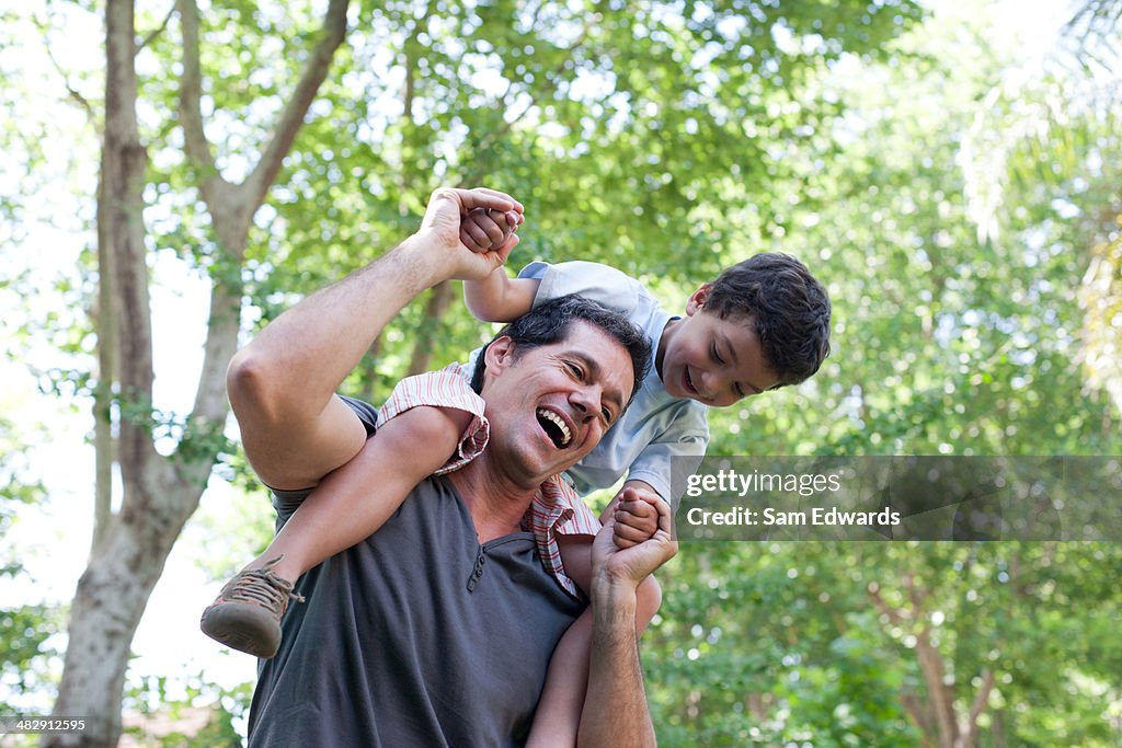 Man outdoors giving smiling young boy shoulder ride 