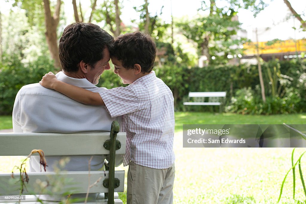 Man outdoors sitting on bench with young boy 