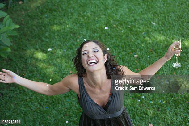 mujer de pie al aire libre en pasto con champán y confeti sonriente - formal garden fotografías e imágenes de stock