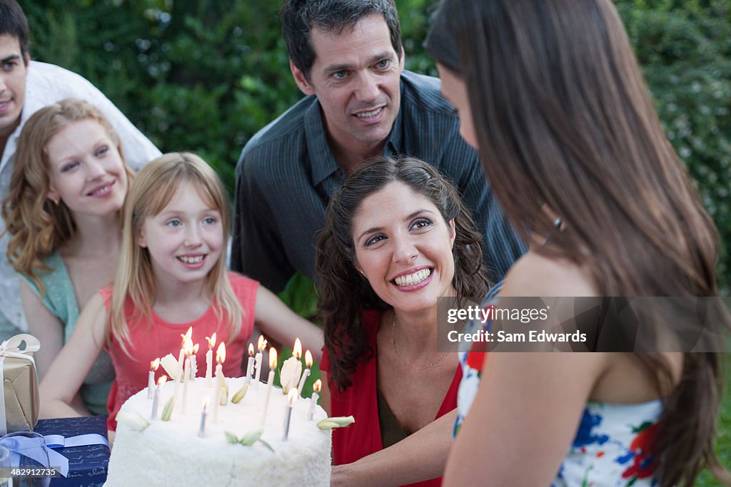 Mulher ao ar livre carregar um bolo de aniversário para uma sorridente pessoas