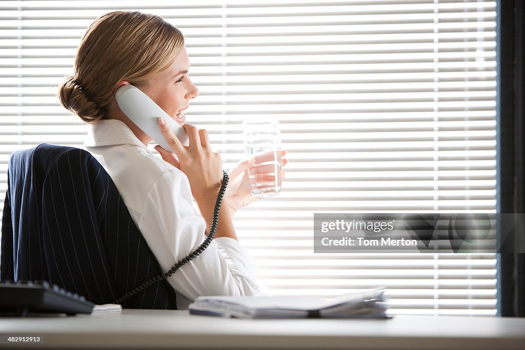 Femme d'affaires assis au bureau parle au téléphone