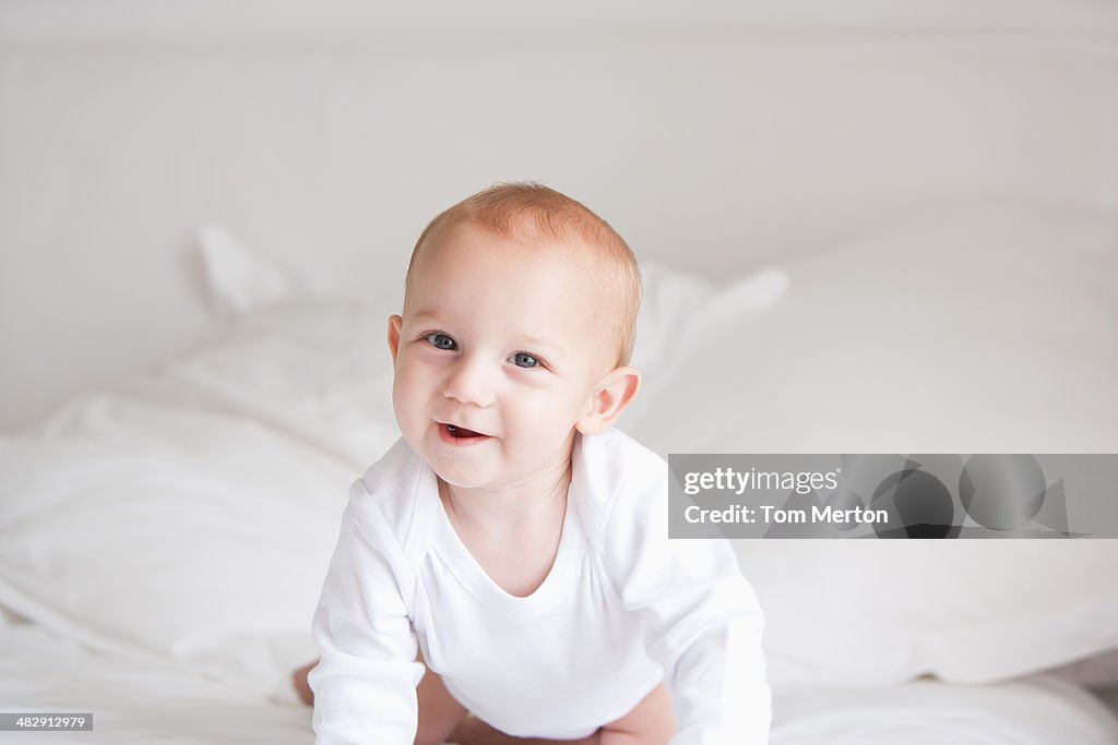 Baby kneeling on bed