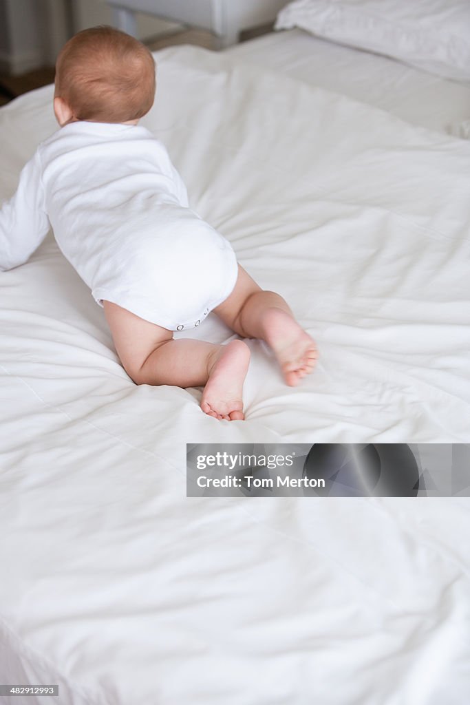 Baby kneeling on bed