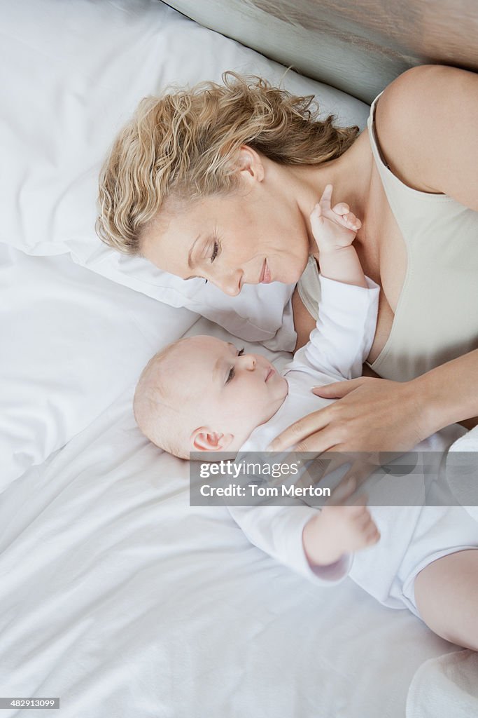 Mother laying on bed with sleeping baby