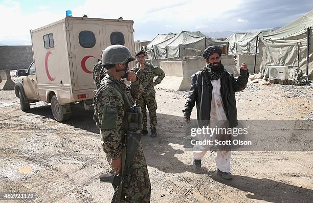 Man with blood-stained clothing tries to help his brother get treatment for a gunshot wound to the chest at the Afghan National Army's Camp Maiwand...