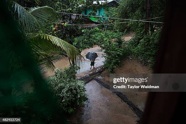 Young resident walks through torrential rain in a village near the planned Dawei SEZ on August 4, 2015 in Pantininn, Myanmar. The controversial,...