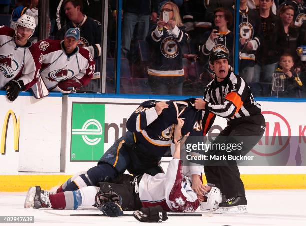 Roman Polak of the St. Louis Blues scuffles with Brad Malone of the Colorado Avalanche as referee Chris Rooney attempts to break it up during an NHL...