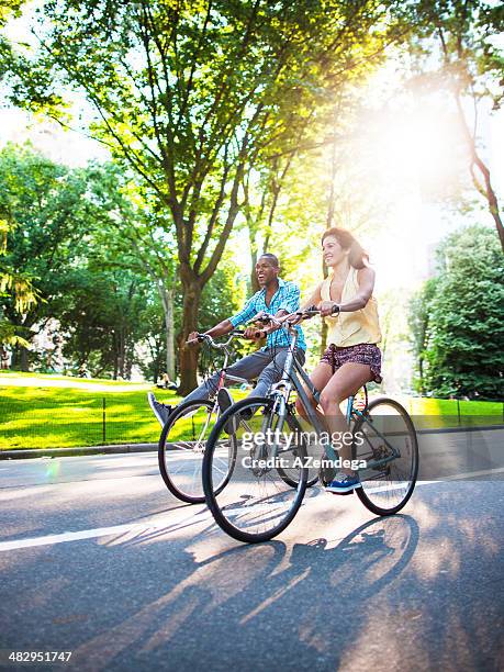 couple in new york city's central park - adult riding bike through park stock pictures, royalty-free photos & images