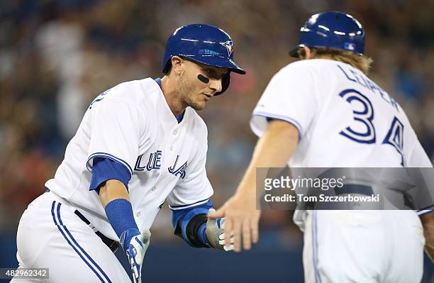 Troy Tulowitzki of the Toronto Blue Jays is congratulated by first base coach Tim Leiper as he hits a solo home run in the third inning during MLB...