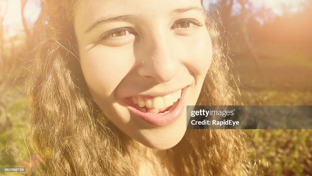 Laughing teenage beauty, distorted by fisheye lens, in fall sunshine