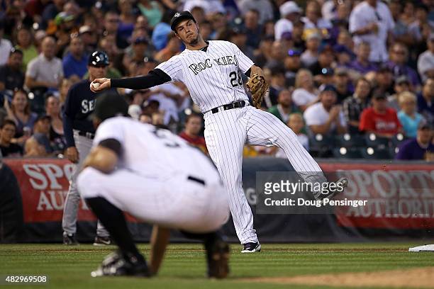 Third baseman Nolan Arenado of the Colorado Rockies fields a ground ball by Nelson Cruz of the Seattle Mariners as pitcher Christian Friedrich of the...