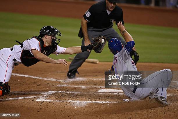 Wilmer Flores of the New York Mets slides safely into home plate past J.T. Realmuto of the Miami Marlins to score a run during the sixth inning of...