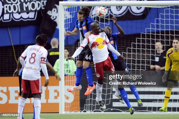 Ian Christianson of the New York RedBulls jumps the head the ball in front of Heath Pearce and Hassoun Camara of the Montreal Impact during the MLS...