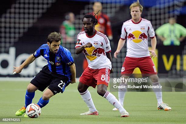 Hernan Bernardello of the Montreal Impact runs with the ball in front of Peguy Luyindula of the New York RedBulls during the MLS game at the Olympic...